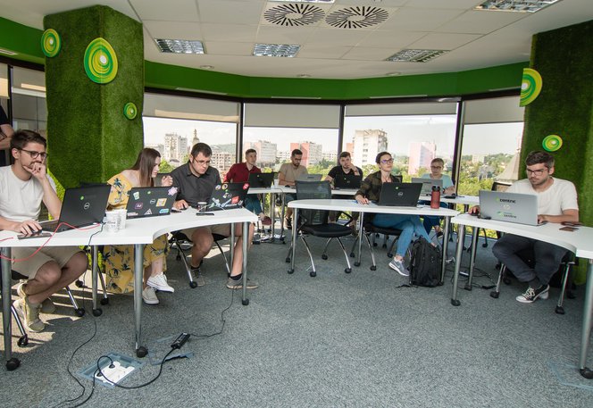 Software developers and QA software testers sitting at tables, working on laptops during a training course